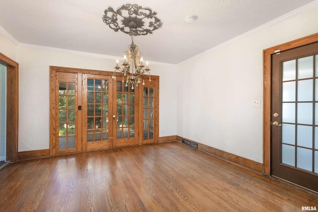 unfurnished dining area with a notable chandelier, wood-type flooring, crown molding, and french doors