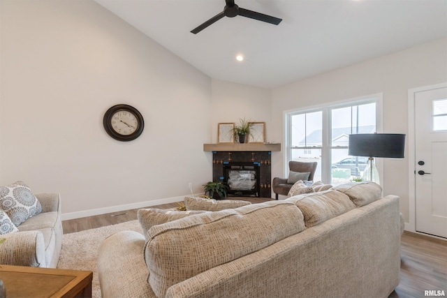 living area featuring a glass covered fireplace, lofted ceiling, wood finished floors, and baseboards