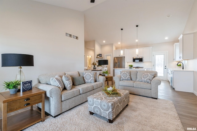 living room featuring recessed lighting, visible vents, light wood-style floors, and high vaulted ceiling