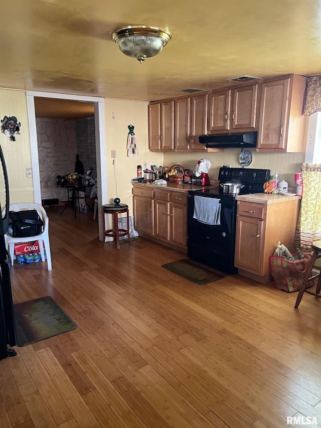 kitchen with black electric range, extractor fan, and hardwood / wood-style floors