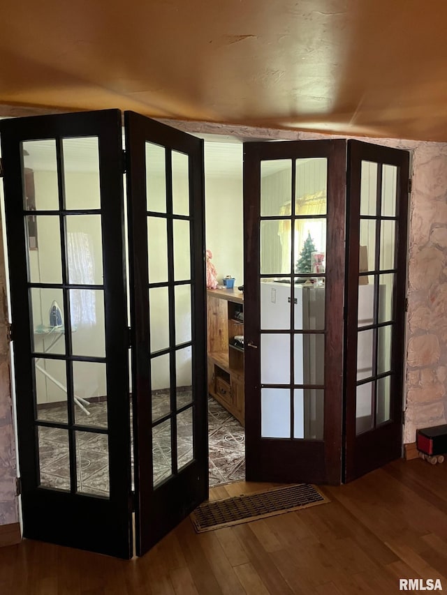 entryway featuring wood-type flooring, french doors, and lofted ceiling