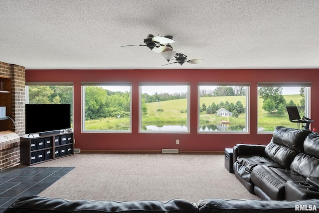 living room featuring plenty of natural light, visible vents, ceiling fan, and carpet flooring