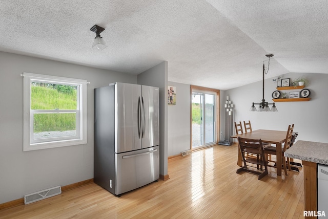 kitchen featuring visible vents, a healthy amount of sunlight, hanging light fixtures, light wood-type flooring, and freestanding refrigerator