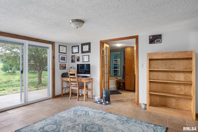 home office featuring a textured ceiling, light tile patterned floors, and baseboards