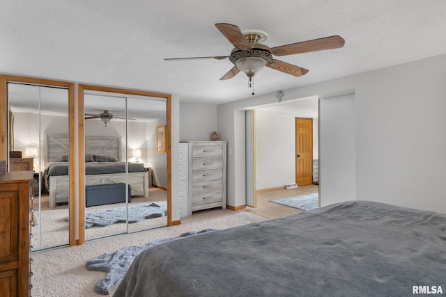 bedroom with a textured ceiling, baseboards, two closets, and light colored carpet