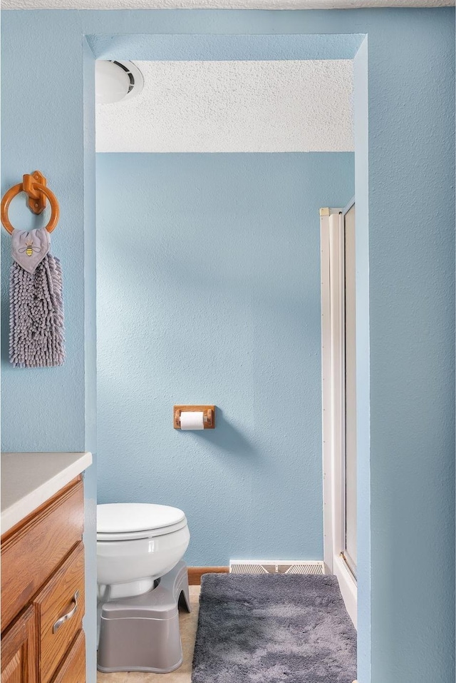 bathroom with vanity, a shower stall, toilet, and baseboards