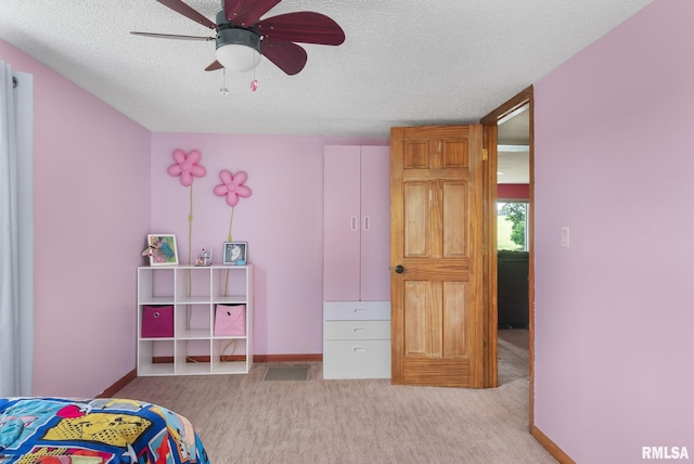 bedroom featuring ceiling fan, baseboards, a textured ceiling, and light colored carpet