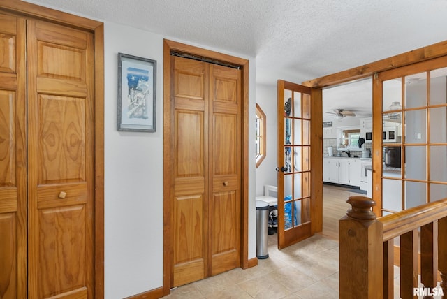 corridor featuring a textured ceiling, french doors, and light tile patterned floors