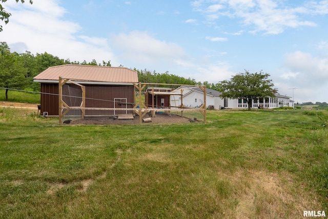 rear view of property featuring a yard, metal roof, and an outdoor structure