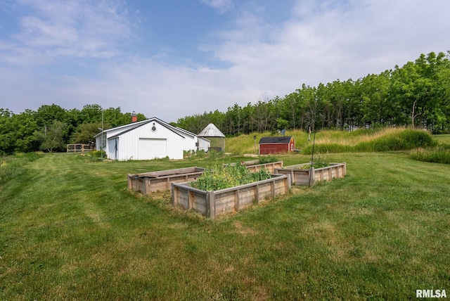 view of yard with a garden, a detached garage, and an outdoor structure