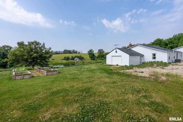 view of yard with a garage, a garden, central AC unit, a water view, and an outdoor structure