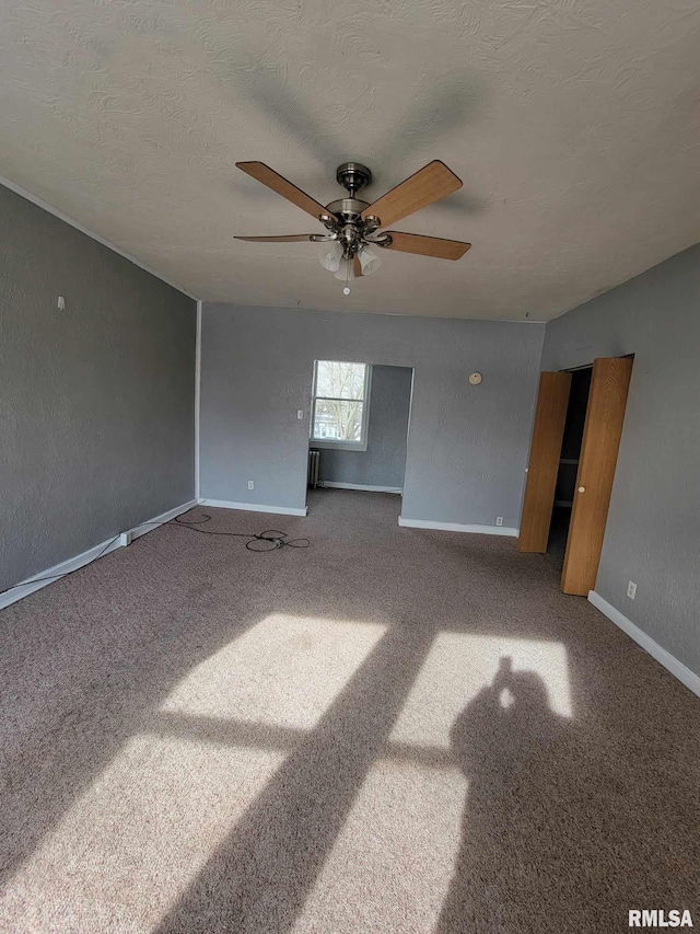 empty room with carpet, a ceiling fan, baseboards, and a textured ceiling