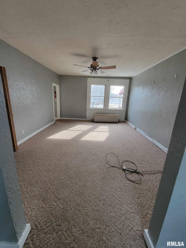 unfurnished room featuring carpet floors, ceiling fan, a textured ceiling, and radiator