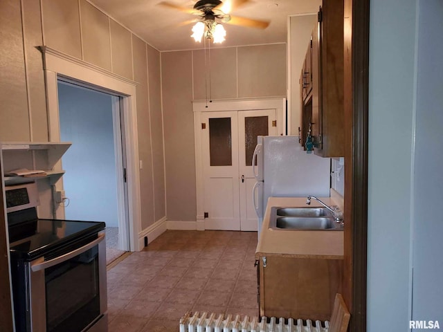 kitchen with a sink, ceiling fan, light countertops, and electric stove