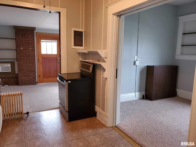 kitchen with a wall unit AC, range with electric cooktop, brick wall, carpet, and radiator