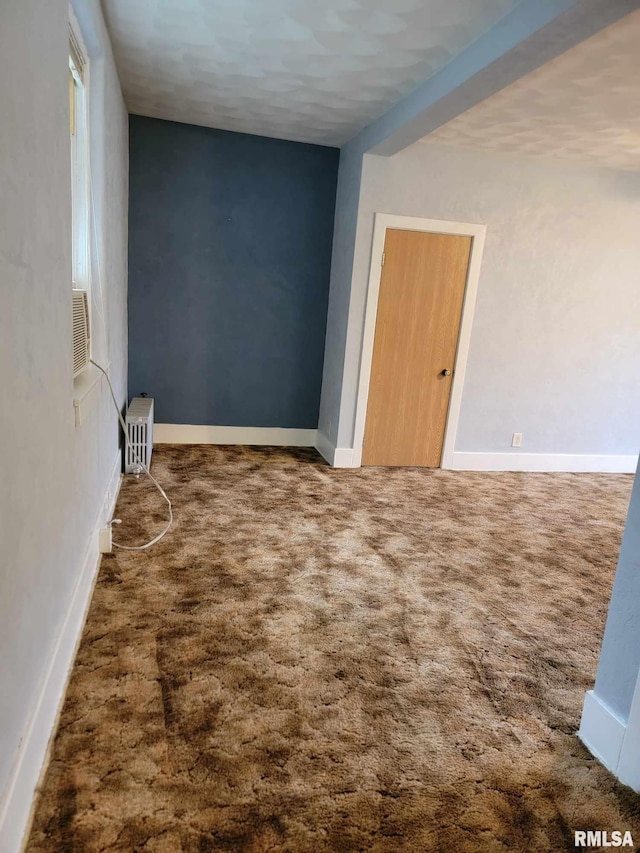 spare room featuring baseboards, carpet, and radiator heating unit