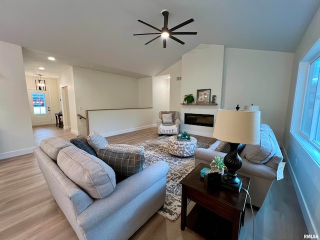 living room with ceiling fan, hardwood / wood-style flooring, a wealth of natural light, and vaulted ceiling