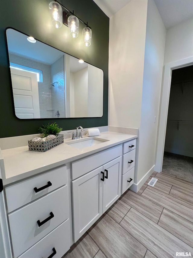 bathroom featuring tiled shower and vanity