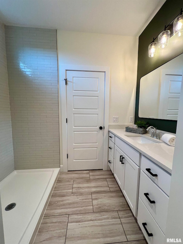 bathroom with vanity and tiled shower