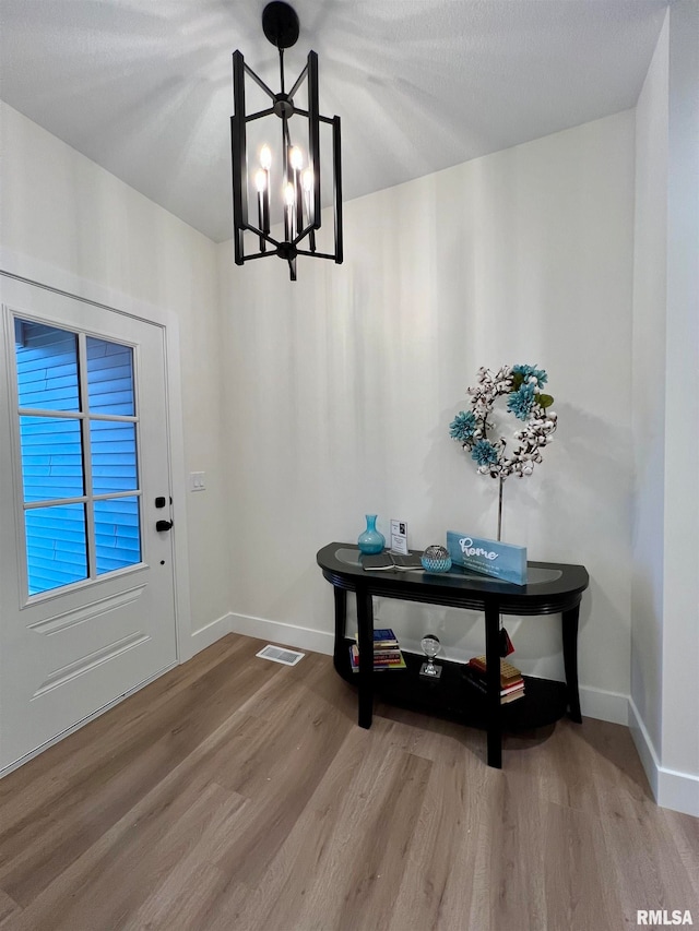 entryway with wood-type flooring and a notable chandelier