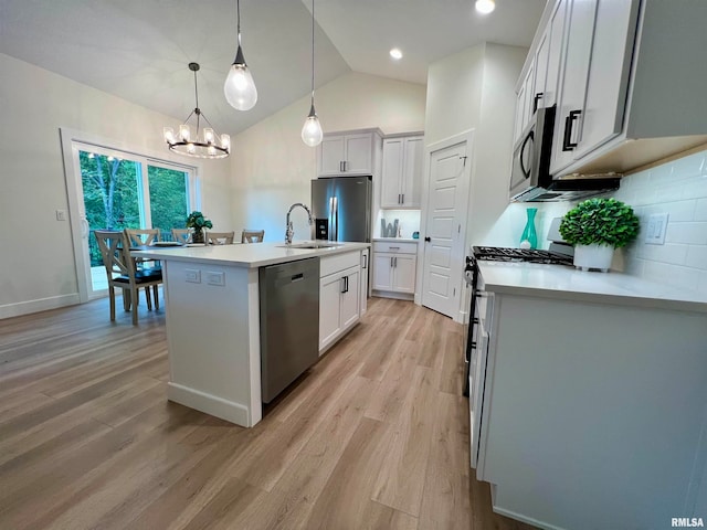 kitchen featuring lofted ceiling, a kitchen island with sink, stainless steel appliances, white cabinetry, and decorative light fixtures