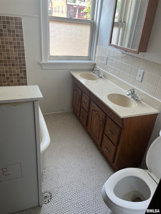 bathroom featuring tile patterned flooring, tasteful backsplash, double vanity, and toilet