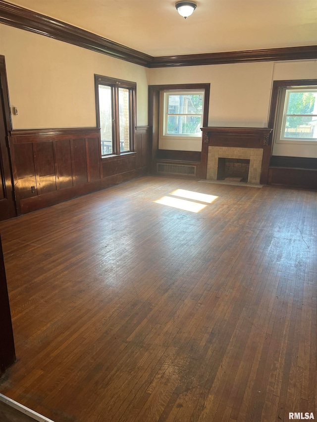 unfurnished living room featuring a wealth of natural light, wood-type flooring, and a tile fireplace