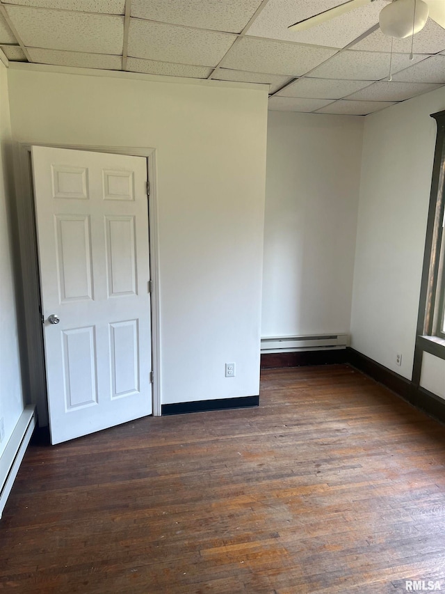 spare room featuring a baseboard radiator, hardwood / wood-style flooring, and a drop ceiling