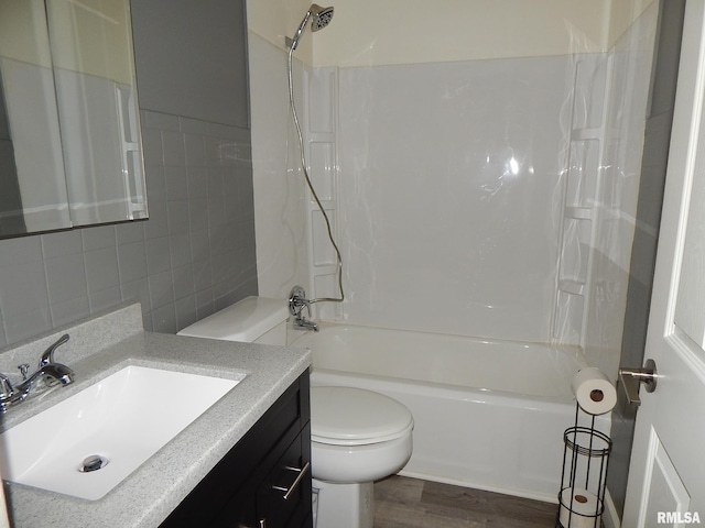 full bathroom featuring shower / bath combination, toilet, vanity, wood-type flooring, and tile walls