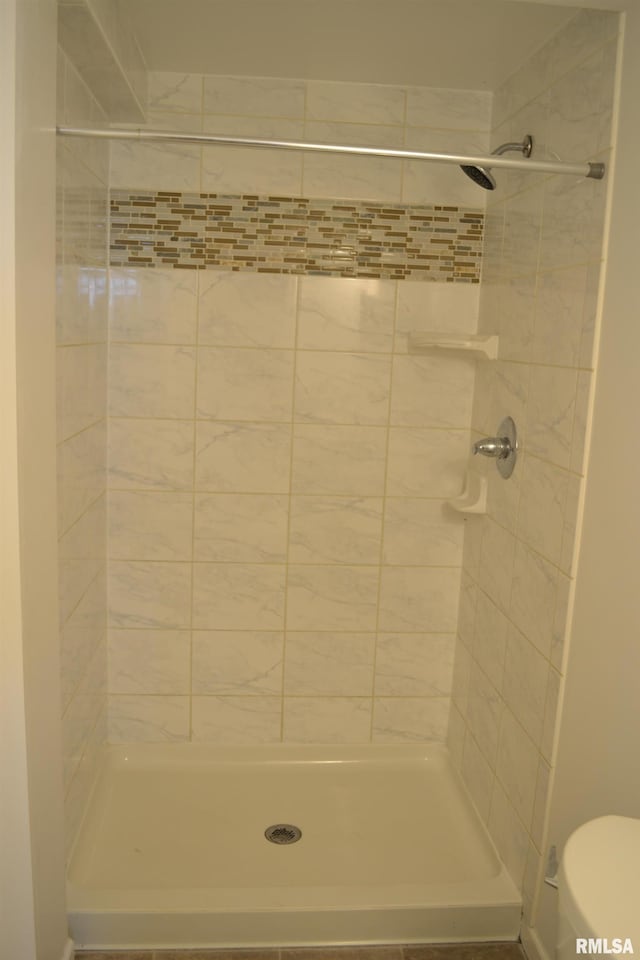 bathroom featuring a tile shower and toilet