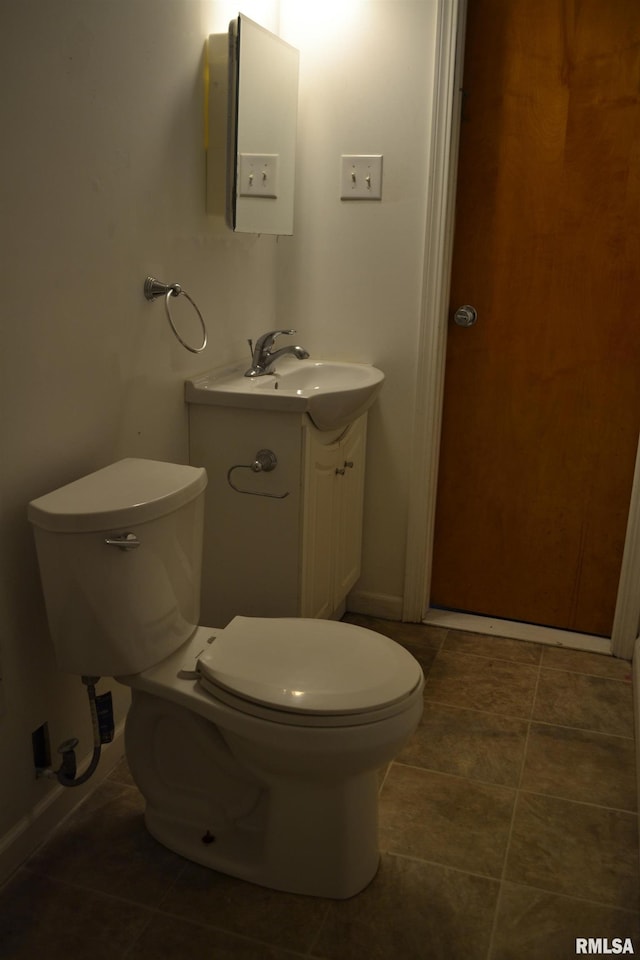 bathroom with toilet, vanity, and tile patterned floors