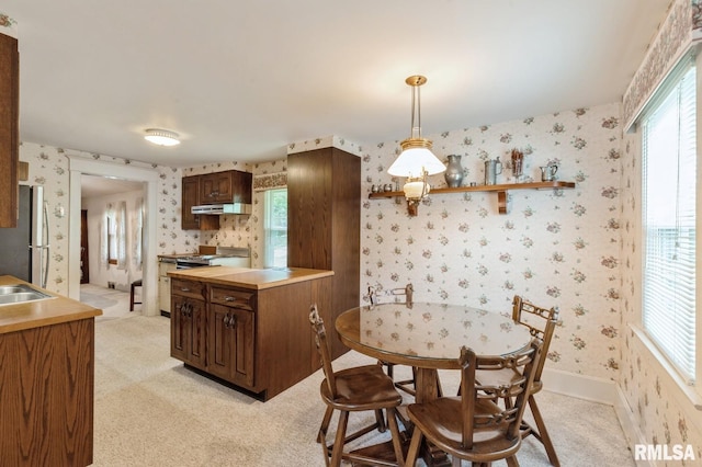 kitchen featuring sink, stainless steel fridge, decorative light fixtures, light colored carpet, and range