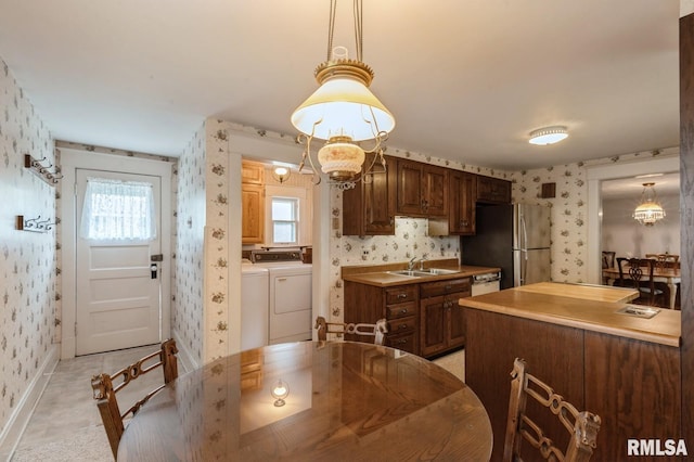 dining area featuring sink, an inviting chandelier, and independent washer and dryer