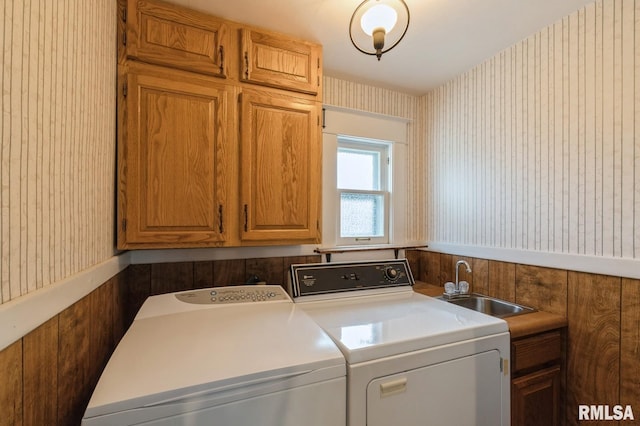 laundry room with separate washer and dryer, wooden walls, sink, and cabinets