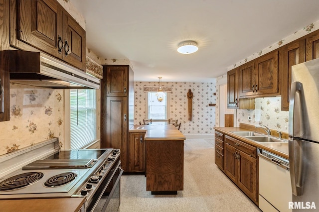 kitchen with stainless steel appliances, hanging light fixtures, light colored carpet, and sink