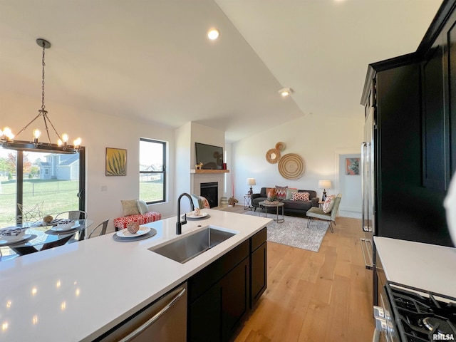 kitchen featuring open floor plan, vaulted ceiling, light countertops, a fireplace, and a sink