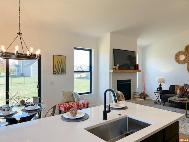 kitchen with a fireplace, a notable chandelier, light countertops, hanging light fixtures, and a sink