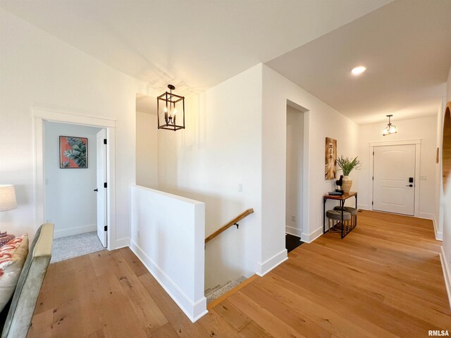 hall with recessed lighting, an upstairs landing, baseboards, light wood finished floors, and an inviting chandelier