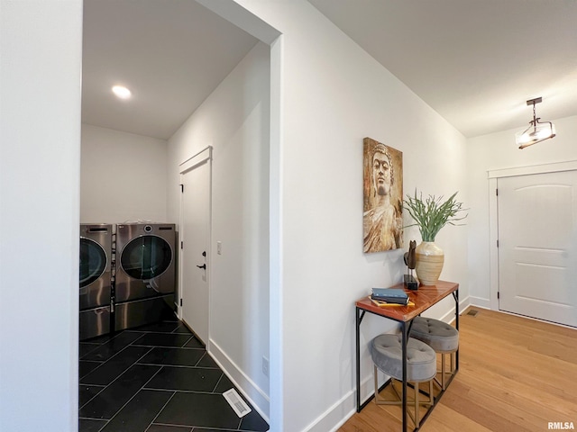 corridor with wood finished floors, washing machine and dryer, visible vents, and baseboards