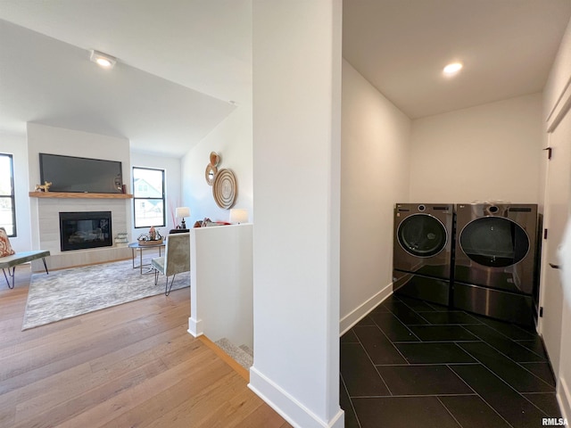 washroom featuring laundry area, a fireplace, wood finished floors, baseboards, and independent washer and dryer