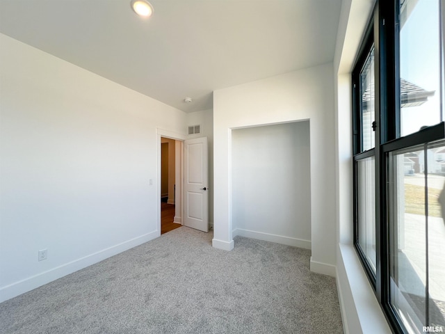 unfurnished bedroom with visible vents, light carpet, baseboards, and multiple windows