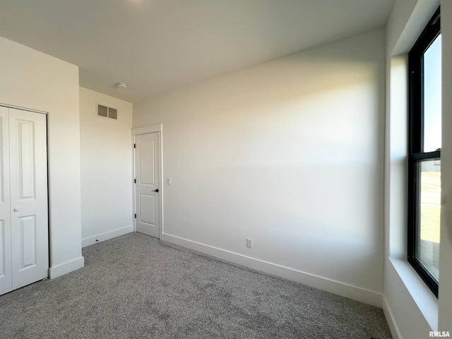 unfurnished bedroom featuring carpet, visible vents, and baseboards