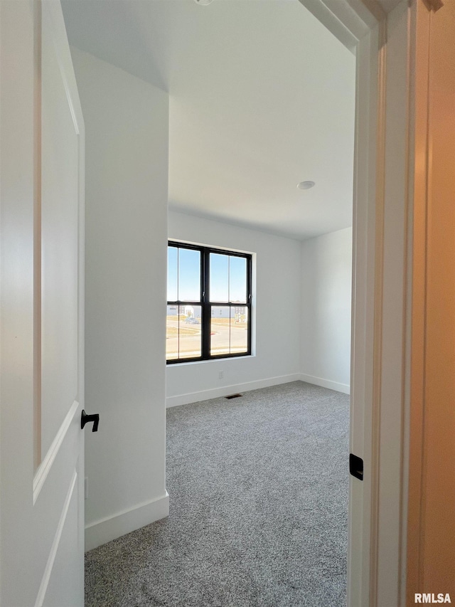 empty room featuring visible vents, baseboards, and carpet flooring