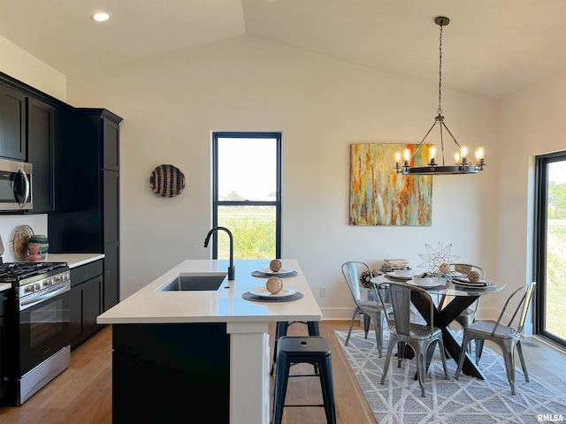 kitchen featuring stainless steel appliances, light countertops, light wood-style floors, vaulted ceiling, and a sink