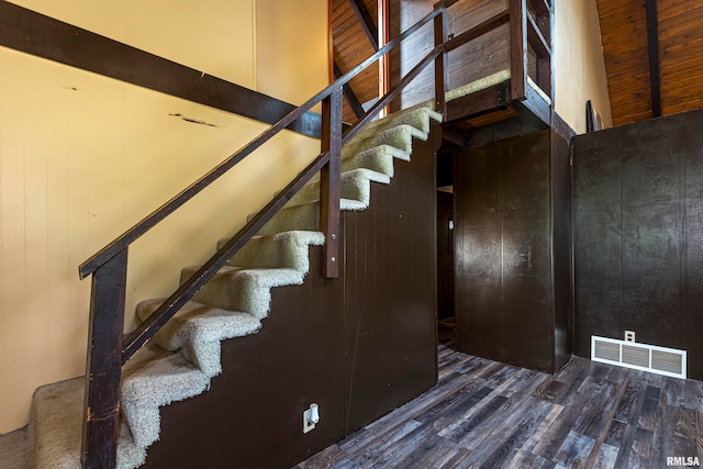 stairway with hardwood / wood-style flooring and a towering ceiling