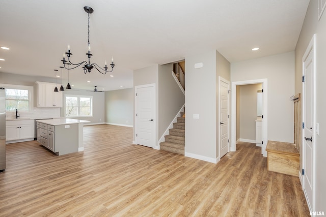 kitchen with a center island, decorative backsplash, pendant lighting, light wood-type flooring, and white cabinetry