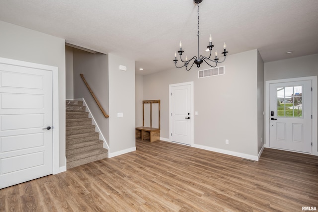 entryway featuring hardwood / wood-style floors, a textured ceiling, and an inviting chandelier