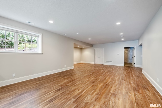 spare room featuring a textured ceiling and light hardwood / wood-style floors