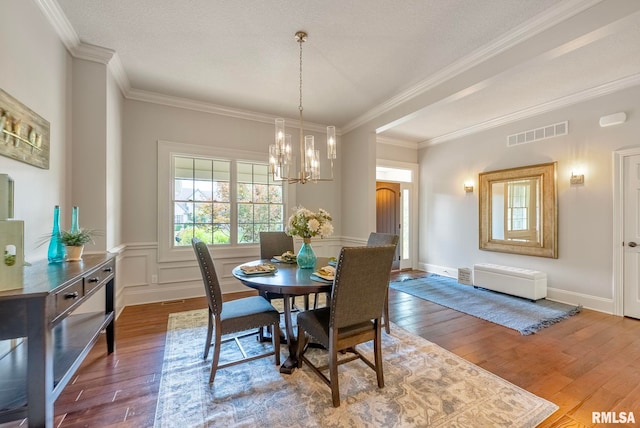 dining space with a chandelier, ornamental molding, and wood-type flooring