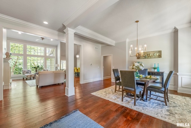 dining space featuring hardwood / wood-style floors, ceiling fan with notable chandelier, decorative columns, and crown molding